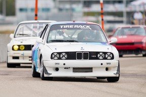 Anthony Kalcouni drives his BMW E30 M3 race car, No.  87, during the heat of competition.